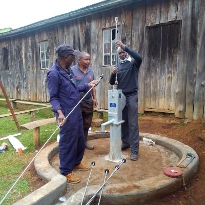 Team installing hand pump on community's new well