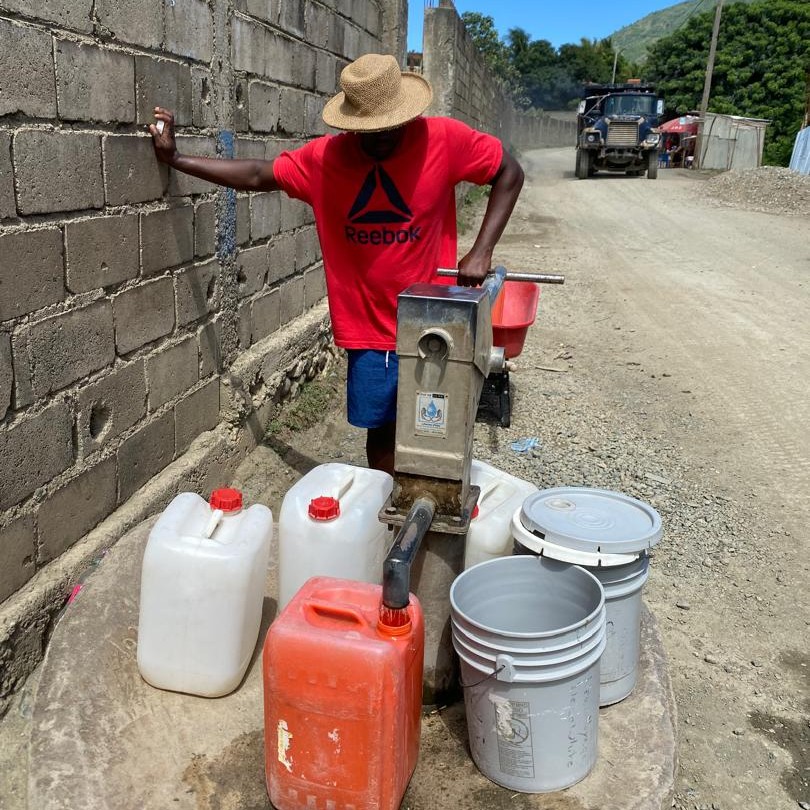 Villager drawing water from repaired pump