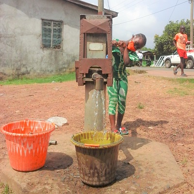 Child drawing water from newly rehabilitated well